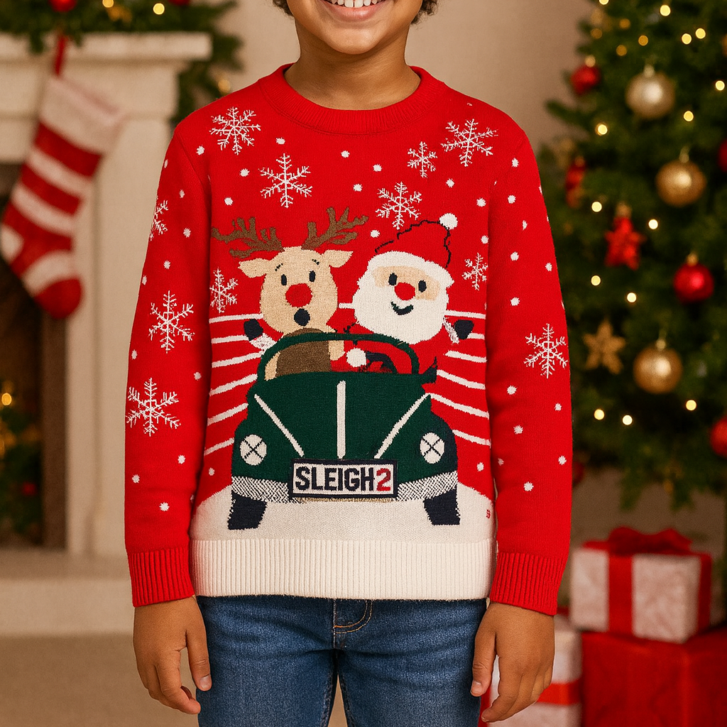 Child wearing a red Christmas sweater with reindeer and sleigh design, standing in front of a decorated Christmas tree and fireplace.